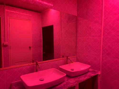 a pink bathroom with two sinks and a mirror at Roxx Social Hostel, Cafe & Bistro in Bangkok