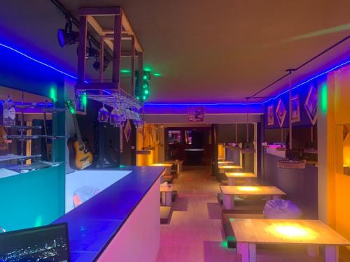 a restaurant with purple and blue lights and tables at Roxx Social Hostel, Cafe & Bistro in Bangkok