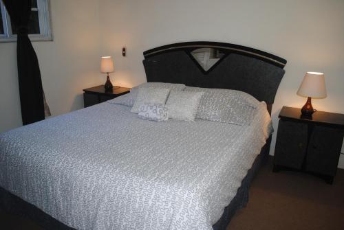 una camera da letto con un grande letto con lenzuola bianche e due lampade di Apart Hotel Valle Verde a San Salvador