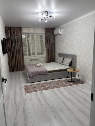 a bedroom with a bed and a table in it at Новая 1 комнатная квартира in Uralsk