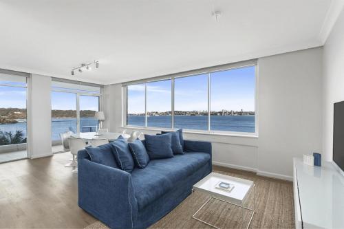 a living room with a blue couch and a table at Mosman Moments Elevated Living on the Harbour - RAG05 in Sydney
