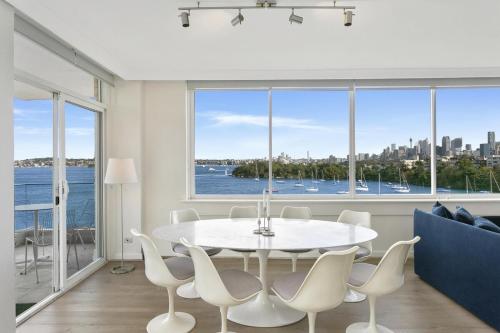 a white dining room with a table and chairs at Mosman Moments Elevated Living on the Harbour - RAG05 in Sydney