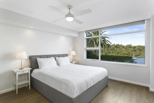 a white bedroom with a bed and a window at Mosman Moments Elevated Living on the Harbour - RAG05 in Sydney