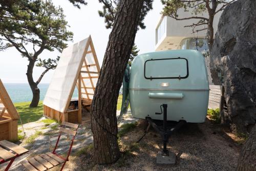 an old blue trailer parked next to a tree at The Moving Caravan 