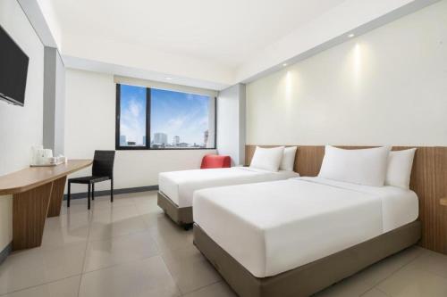 Una habitación de hotel con dos camas, un escritorio y una computadora. en Indies Style Hotel Bandung, en Bandung