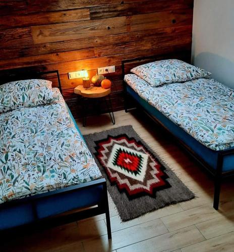 a bedroom with two beds and a table with a rug at Wilczy Domek Cisna in Cisna