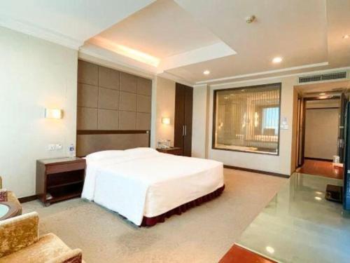 a bedroom with a large white bed and a bathroom at Changchun Zhuozhan Days Hotel in Changchun