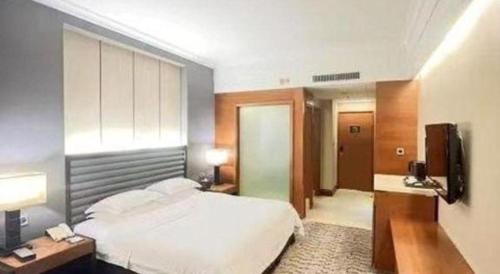 a bedroom with a bed and a desk and a television at King Century Hotel in Zhongshan