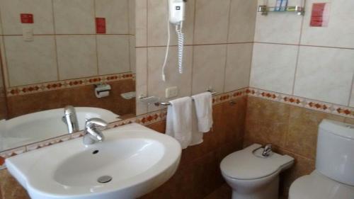 Un baño con lavabo, inodoro y teléfono. en Hotel Colomba, en Huaraz