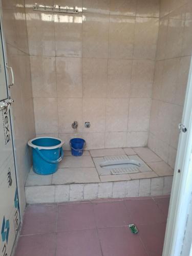 a shower with two blue buckets in a bathroom at Narmada Guest House in Indore