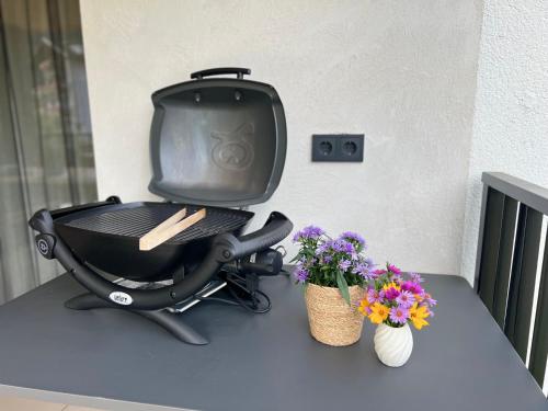 a grill sitting on top of a table with flowers at Apart Bieles NEU - Bergoase mit privater Outdoor-Sauna & Massagepraxis in Kauns