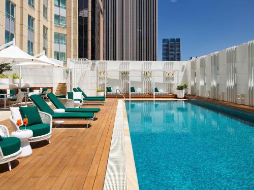 a pool on the rooftop of a hotel with lounge chairs at Swissotel Sydney in Sydney