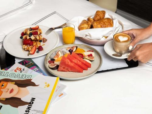a table topped with plates of breakfast foods and coffee at Swissotel Sydney in Sydney