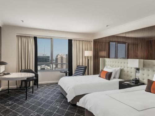 a hotel room with two beds and a desk at Swissotel Sydney in Sydney