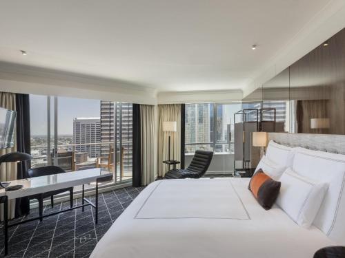 a bedroom with a large white bed and a desk at Swissotel Sydney in Sydney