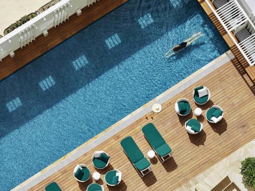 an overhead view of a swimming pool with chairs and a person swimming at Swissotel Sydney in Sydney
