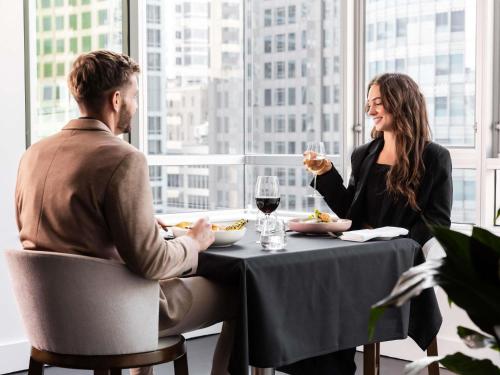a man and a woman sitting at a table eating food at Swissotel Sydney in Sydney