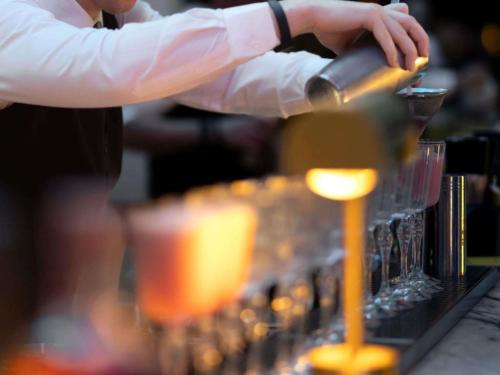 a bartender is preparing drinks in glasses on a bar at Swissotel Sydney in Sydney