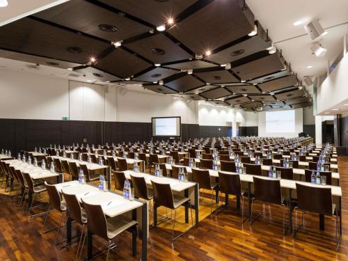 a large room with tables and chairs and a screen at Swissotel Tallinn in Tallinn