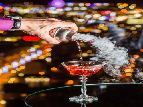 a person pouring a drink into a martini glass at Swissotel Tallinn in Tallinn