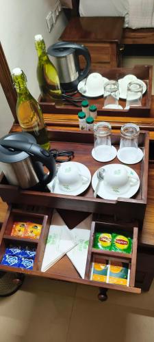 a wooden table with plates and dishes on it at Monica Garden Bungalow in Vālpārai