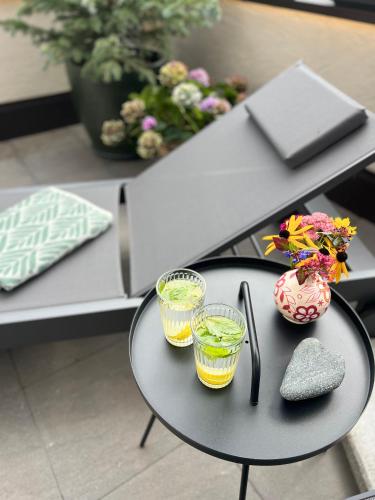 a black table with two glasses and a vase with flowers at Apart Bieles NEU - Bergoase mit privater Outdoor-Sauna & Massagepraxis in Kauns