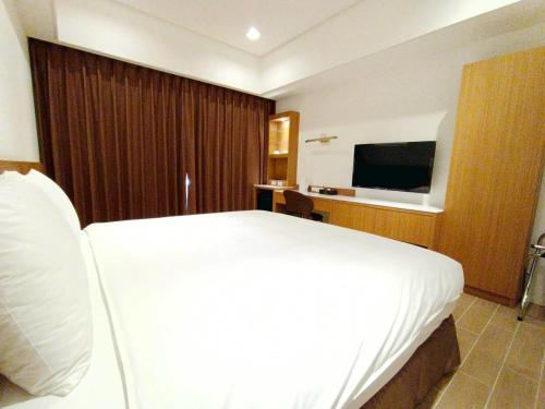 a hotel room with a bed and a television at Mille Rich Hotel in Taitung City