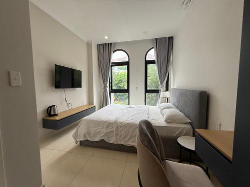 a bedroom with a bed and a tv and windows at Three women in Phu Quoc