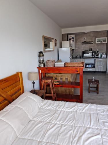 a bedroom with a bed and a desk and a kitchen at Asturiano 6 Miramar in Miramar