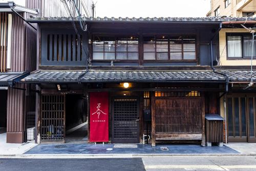 un bâtiment avec un panneau rouge devant lui dans l'établissement Rinn Kishoan, à Kyoto