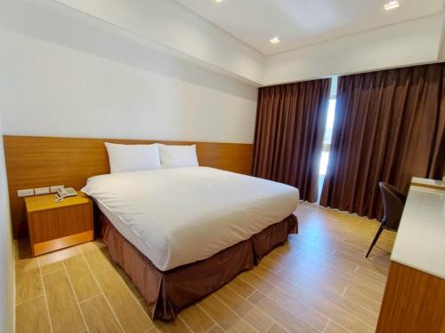a bedroom with a large bed in a hotel room at Mille Rich Hotel in Taitung City