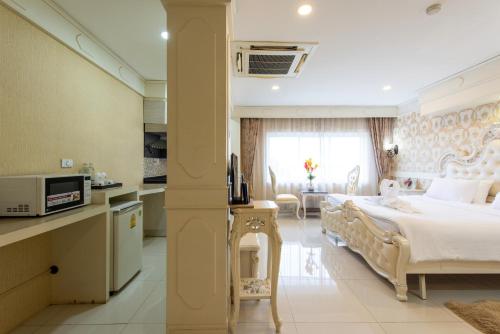 a bedroom with a large bed and a kitchen at Chokdee Place in Sakon Nakhon