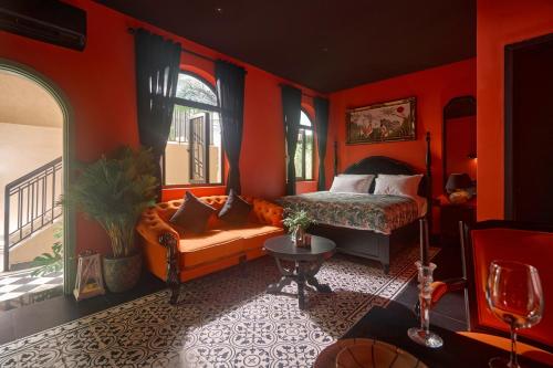 a bedroom with orange walls and a bed and a couch at G'Villa Thảo Điền in Ho Chi Minh City