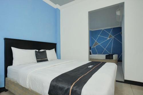 a bedroom with a large bed with a blue wall at Hotel O Palembang near Palembang Indah Mall formerly Hotel Relasi in Palembang