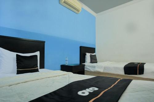 two beds in a room with blue lights at Hotel O Palembang near Palembang Indah Mall formerly Hotel Relasi in Palembang