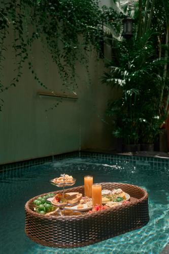 a tray of food on a table in a swimming pool at G'Villa Thảo Điền in Ho Chi Minh City