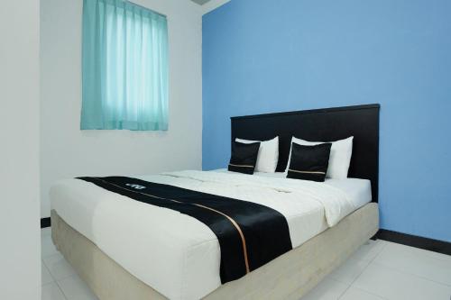 a bedroom with a large bed with a blue wall at Hotel O Palembang near Palembang Indah Mall formerly Hotel Relasi in Palembang