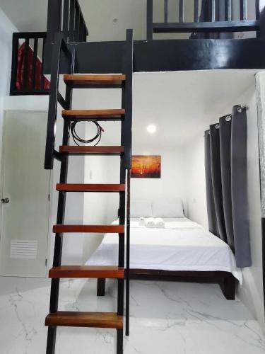 a loft bed with a ladder in a room with a bed at Villa Kendra in Moalboal