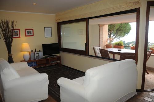 a living room with two white chairs and a television at Appartamento Sabatinus in Trevignano Romano