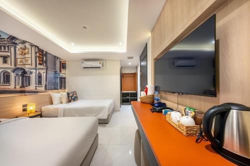 a hotel room with a bed and a flat screen tv at U TOR Yaowarat in Bangkok