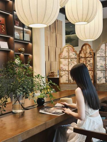 una mujer sentada en una mesa en una tienda en Ayata Hotel, en Chengdú