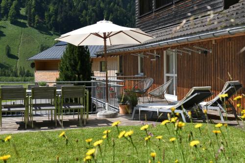 a deck with a table and an umbrella and chairs at Ferienwohnung Lingg in Schoppernau