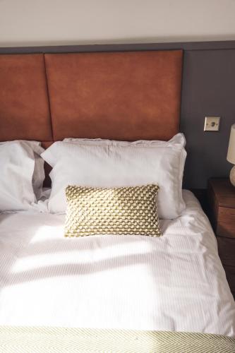 a white bed with a brown headboard and a pillow at The Cherry Tree Inn in Nuffield