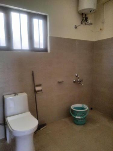 a bathroom with a toilet and a window and a bucket at Dasukbnb in Shillong