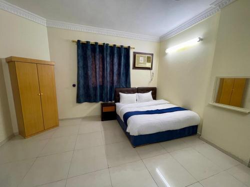a bedroom with a bed with a blue curtain and a window at سبل الذهبية للشقق المخدومة in An Naqāʼ
