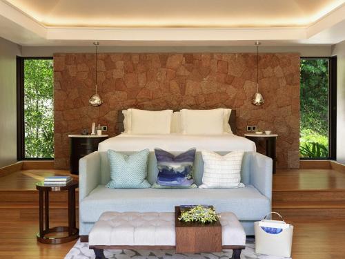a bedroom with a large bed and a couch at Raffles Seychelles in Baie Sainte Anne