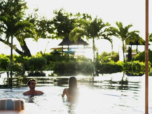 a man and a woman in a swimming pool at Raffles Seychelles in Baie Sainte Anne