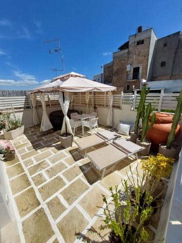 a patio with an umbrella and chairs and plants at Siramà Suite Deluxe in Oria