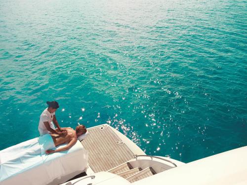 a man and woman sitting on the back of a boat in the water at Raffles Seychelles in Baie Sainte Anne