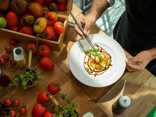 a person holding a plate of food on a table with tomatoes at Fairmont Bab Al Bahr in Abu Dhabi